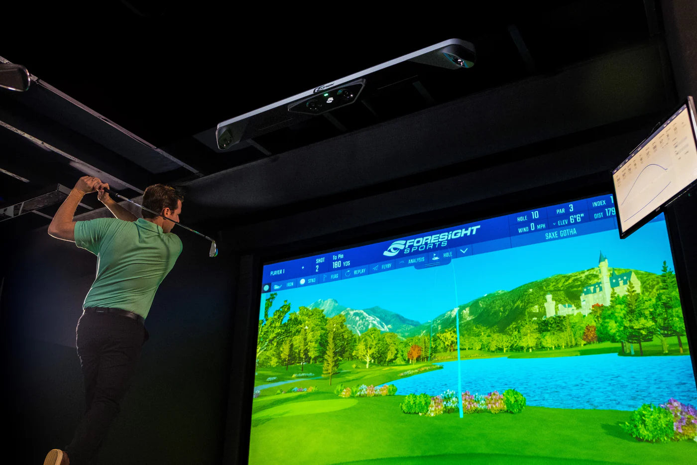 GCHawk Launch Monitor in use, golfer taking a swing in a professional overhead golf simulator setting.